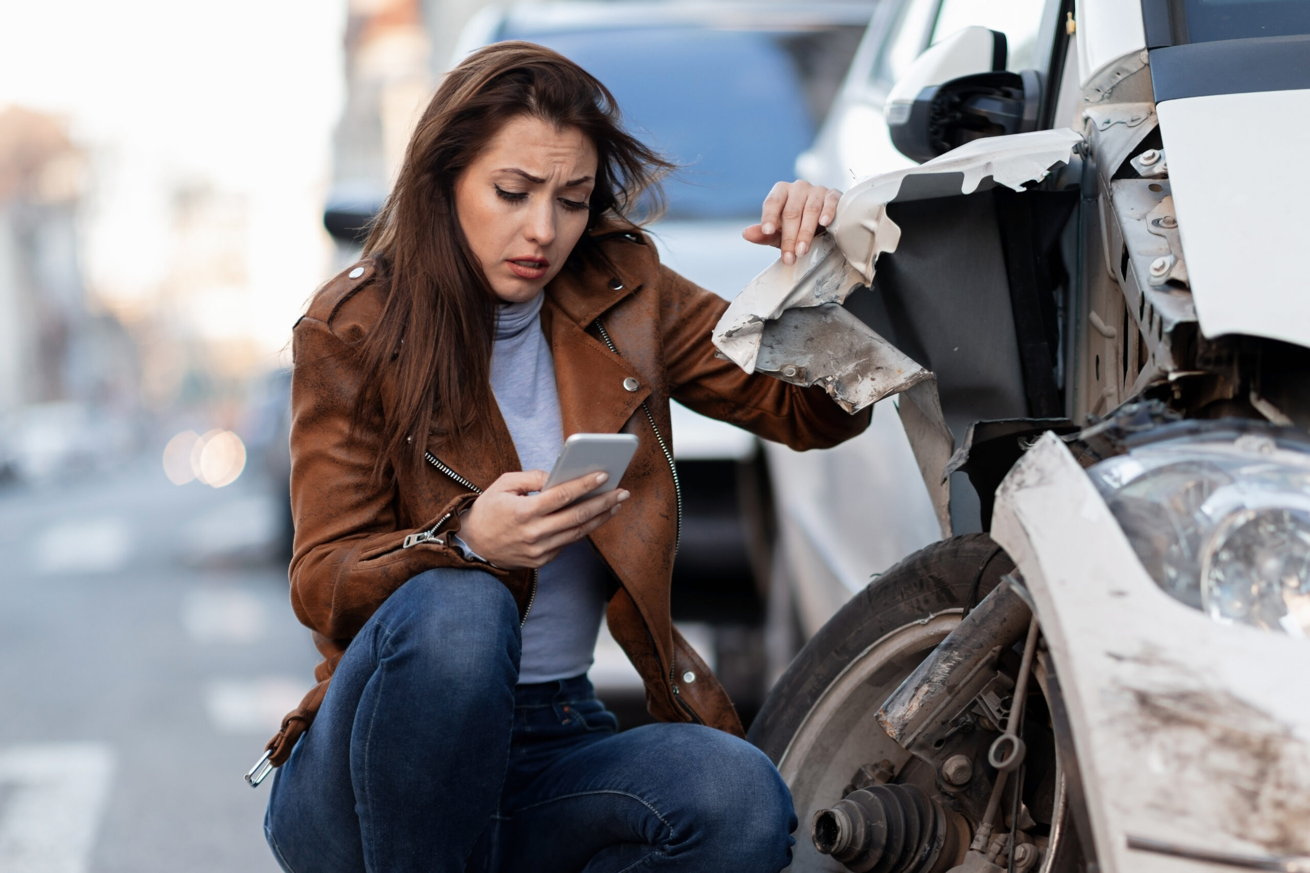 displeased woman dialing for help after a car accident in the city.